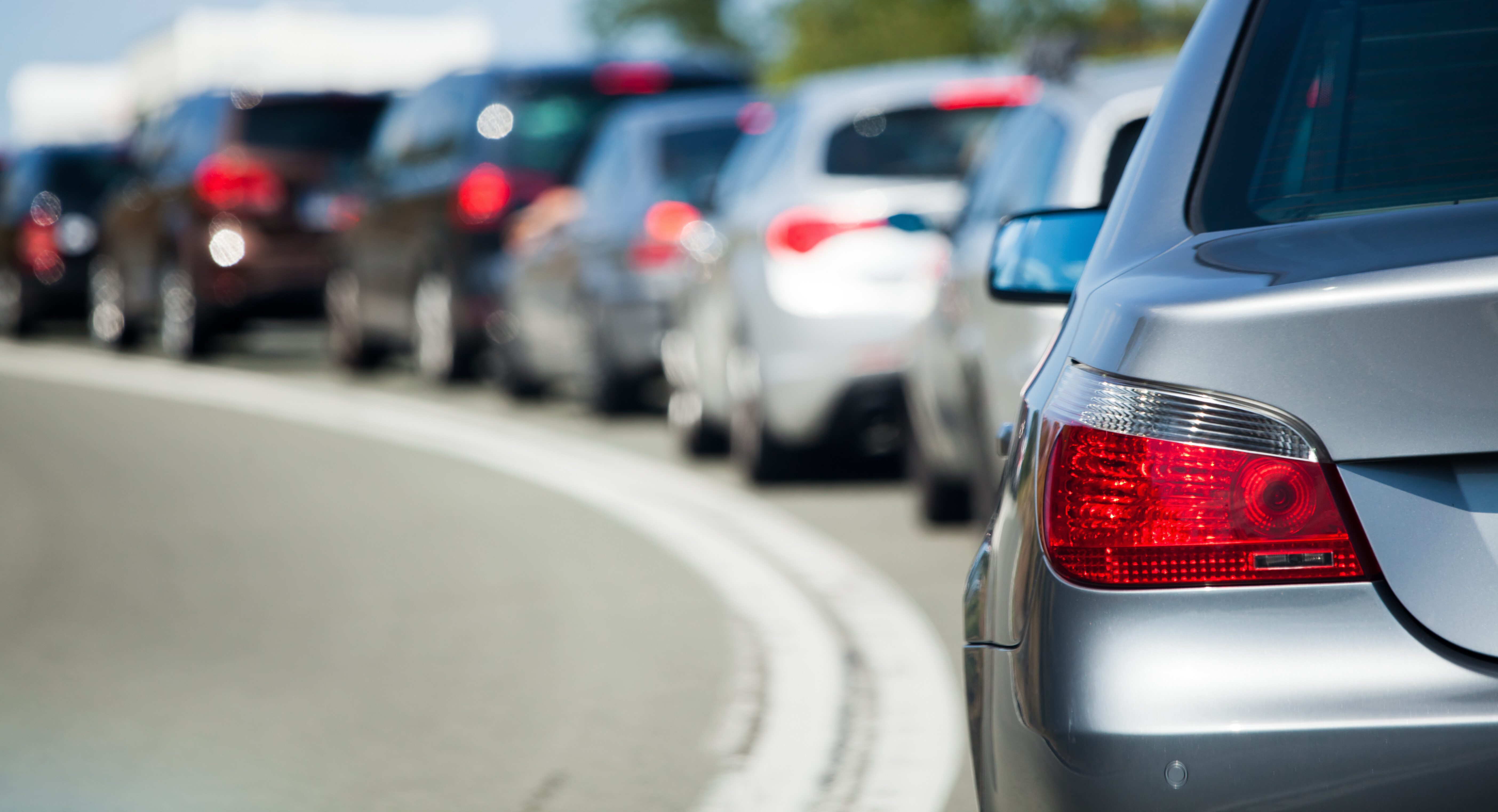 Ein Stau: Mehrere Rücklichter von Autos, die hintereinander im Stau stehen.