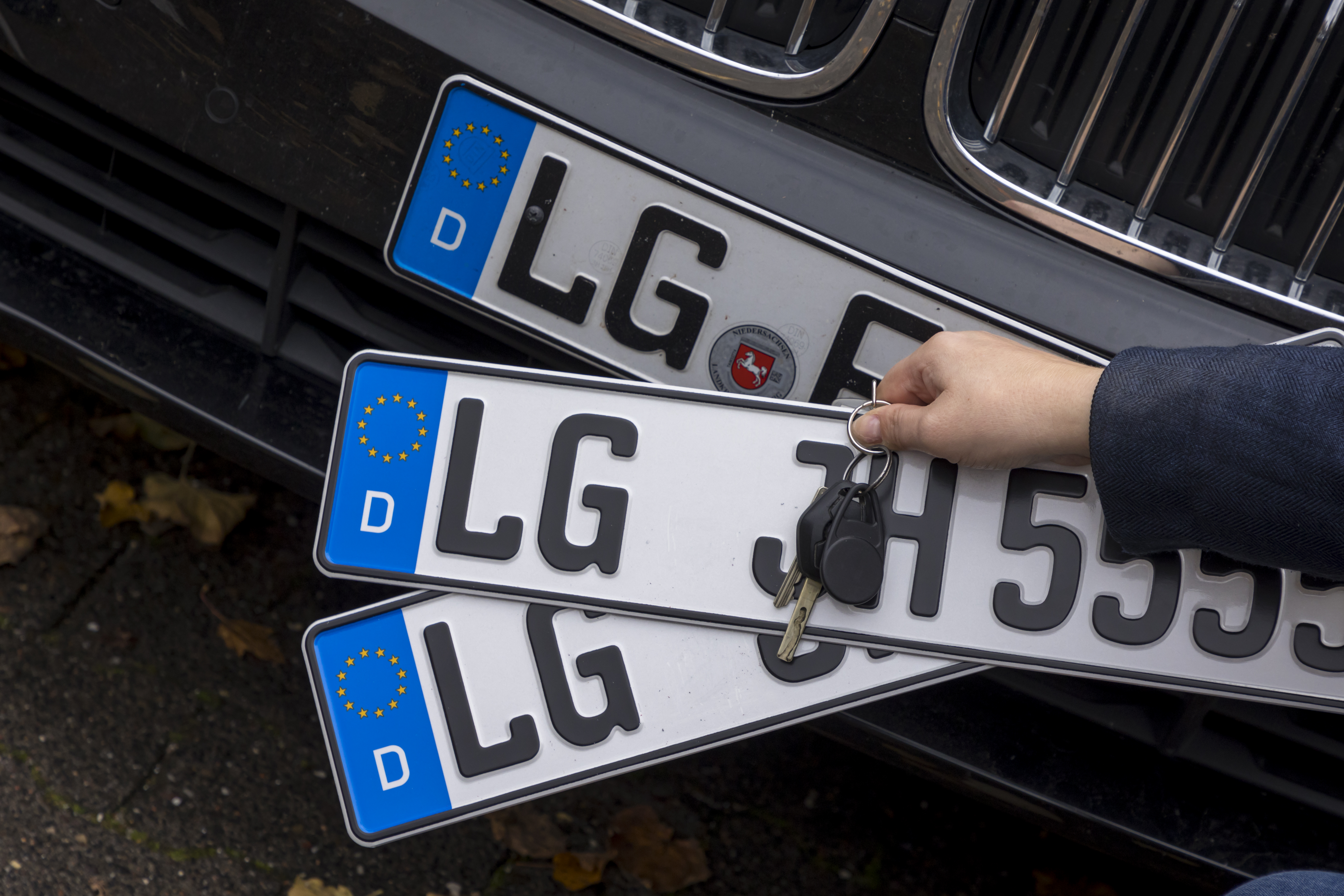 Drei Autokennzeichen mit LG für Lüneburg und ein Autoschlüssel.