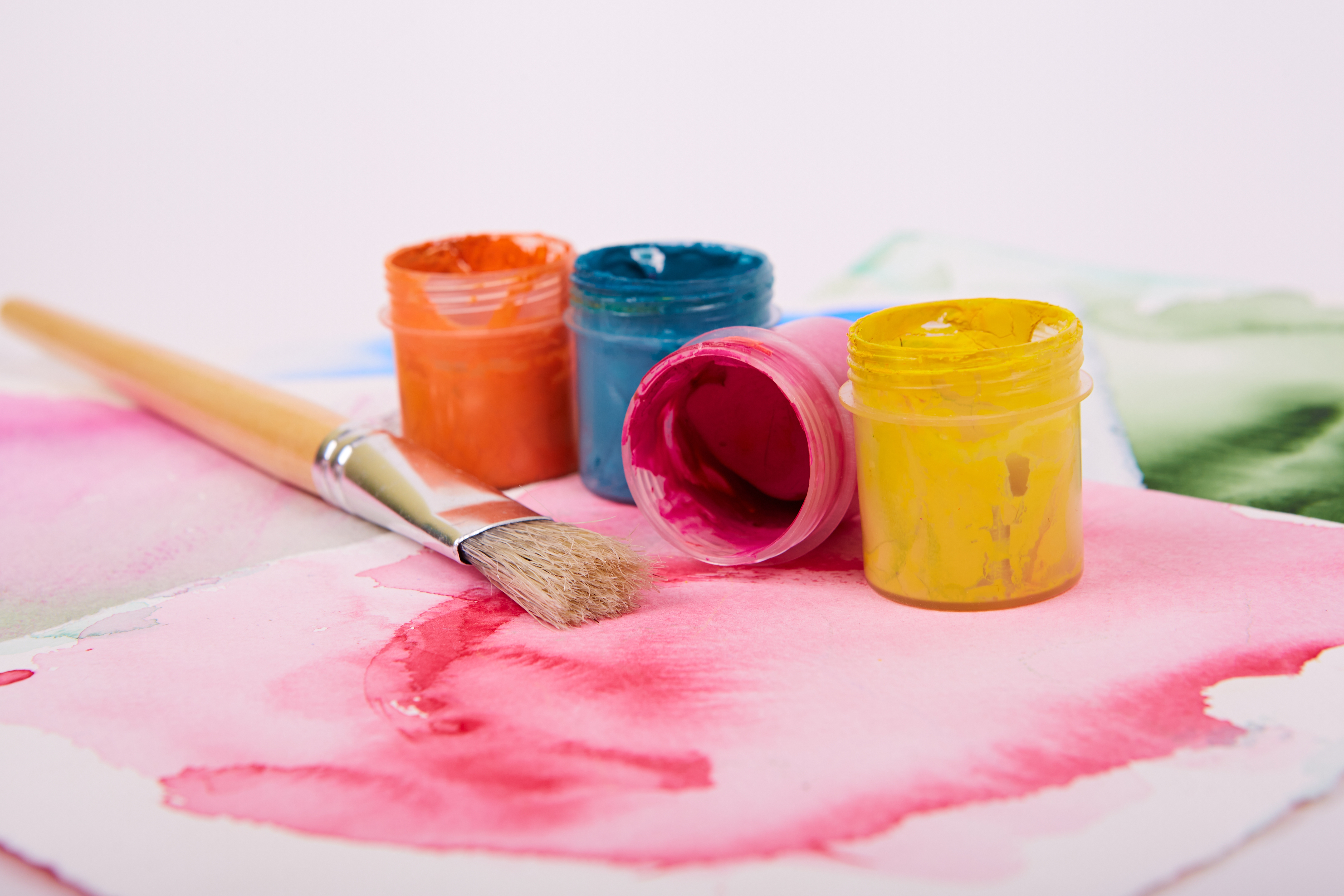 Farbtöpfe neben einem Pinsel. 