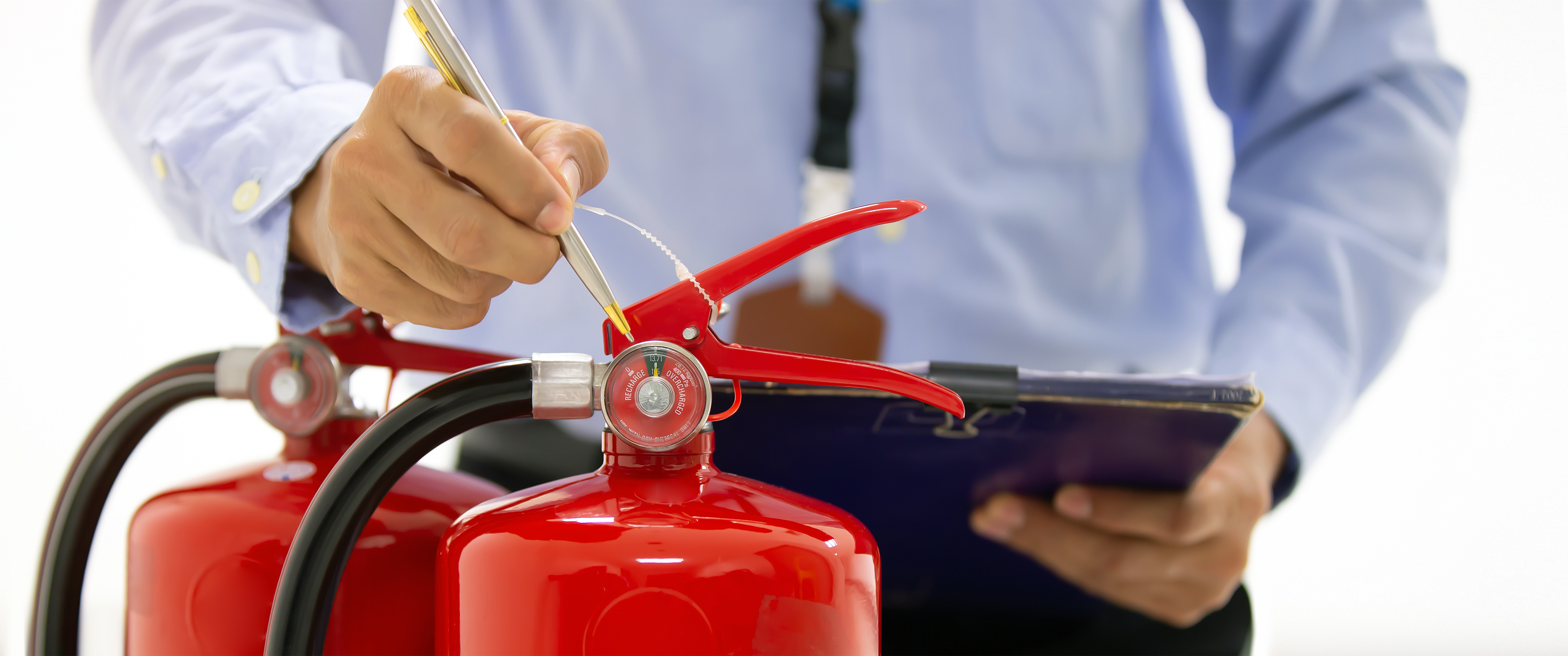 Ein Mann überprüft zwei neue Feuerlöscher.