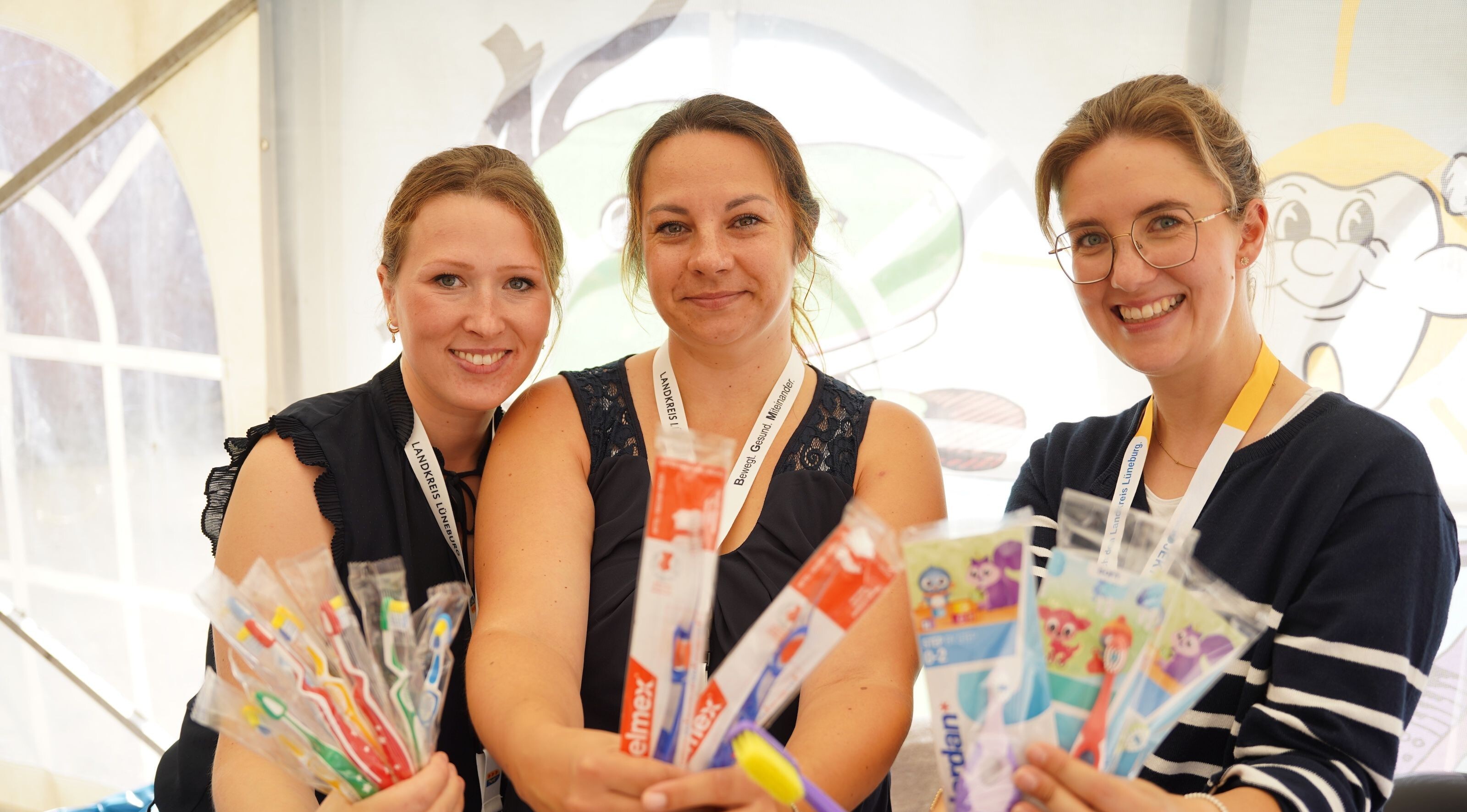 Viele verschiedene Zahnbürsten in einer Reihe auf braunem Hintergrund.