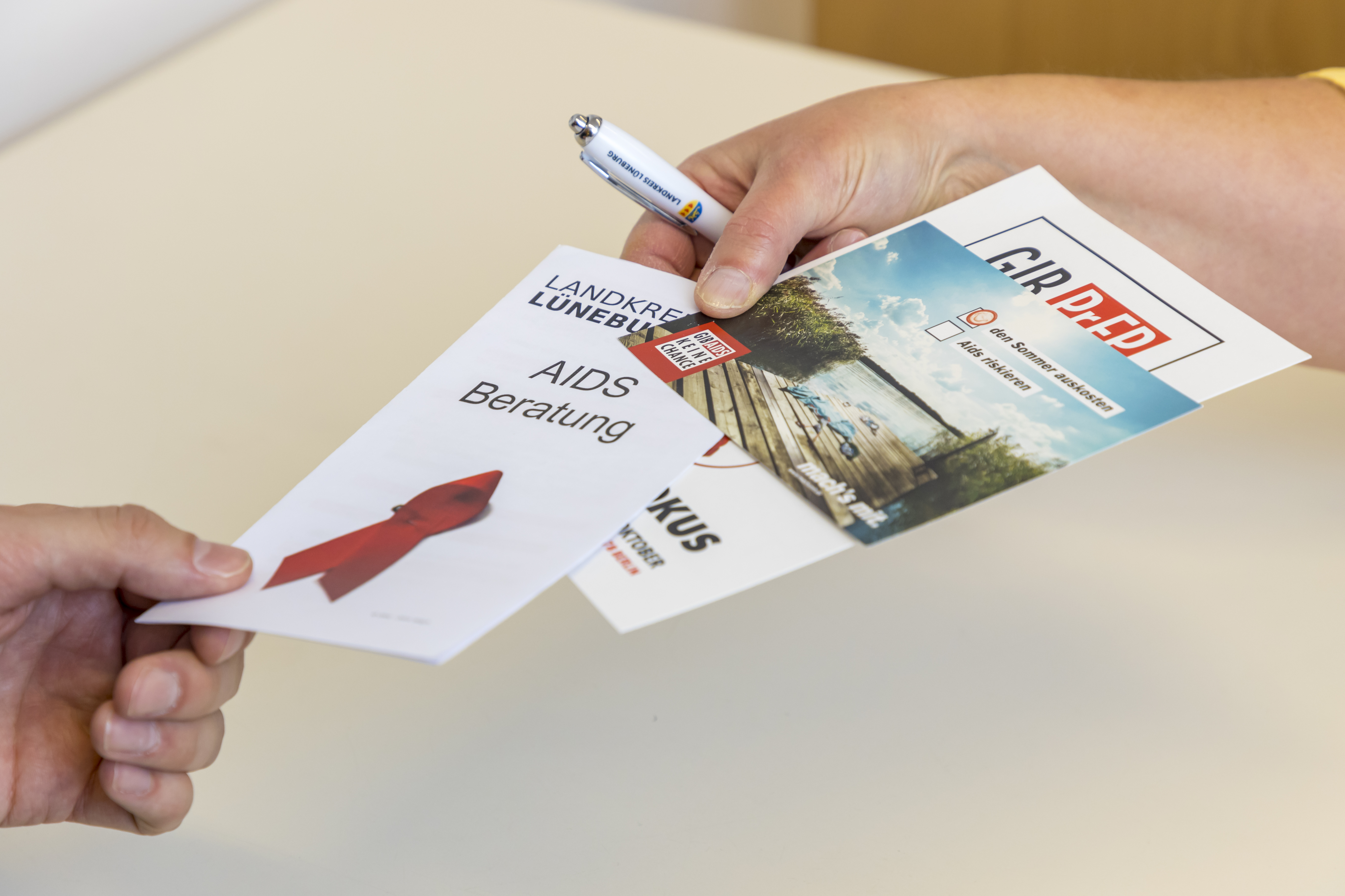 Eine Person überreicht einer anderen Informationsmaterial über HIV und Aids.