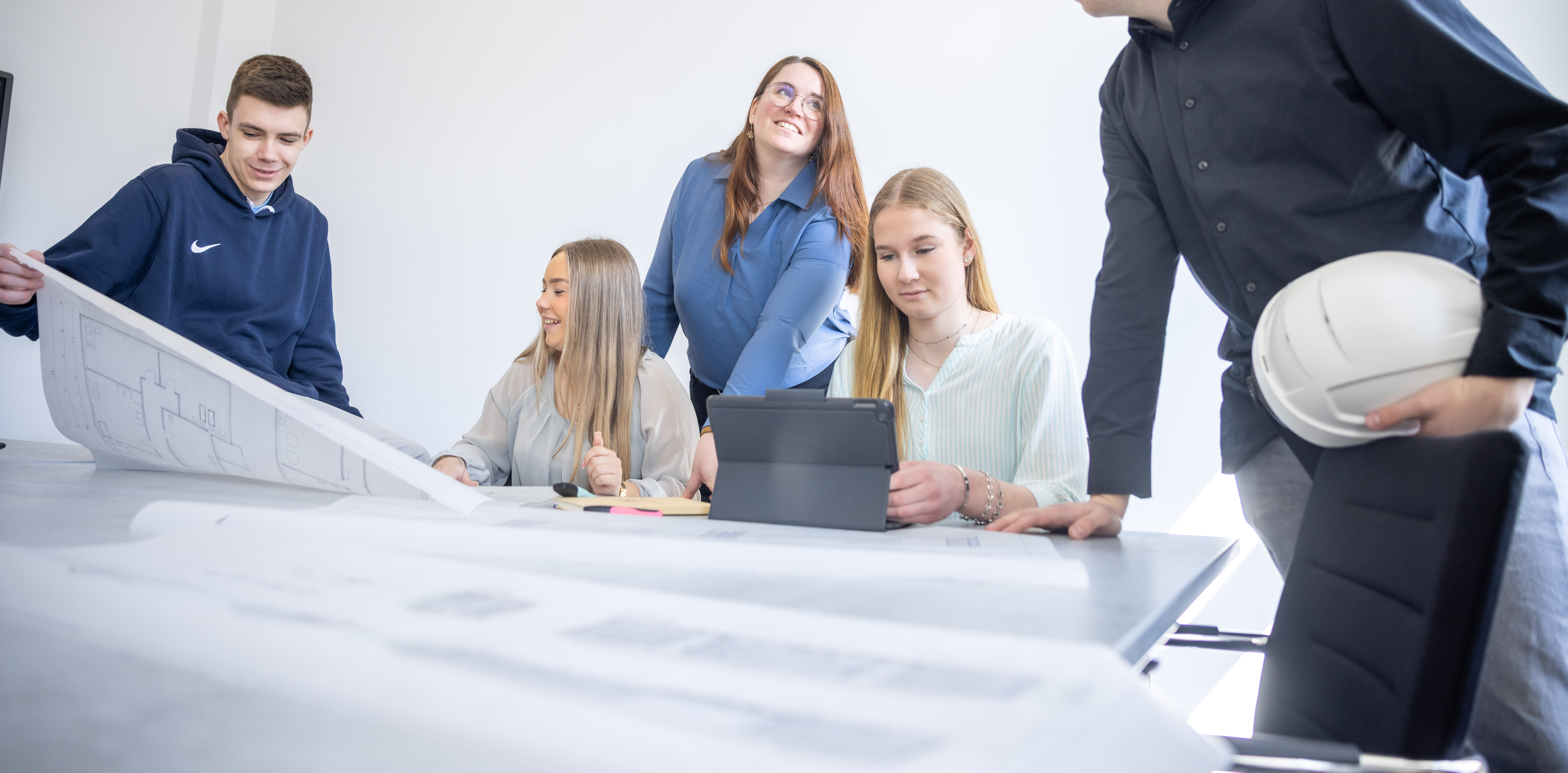 Architektenutensilien: Bauhelm, Bauplan, Kopfhörer und Wasserwaage.